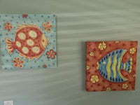 two paintings of fish hanging on the wall